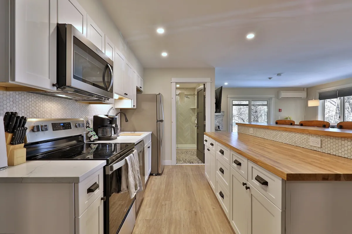 A welcoming kitchen scene with a central island, stainless steel appliances, a striking hexagonal backsplash, and a wooden countertop. The space is set up for family gatherings, cooking together, and entertaining, with ample room for shared meals.