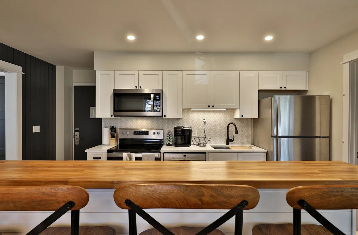 This image showcases the heart of the kitchen, featuring a spacious kitchen island, sleek stainless steel appliances, and modern cabinetry. The setup is ideal for meal prep and socializing, with inviting lighting and an overall sense of warmth and functionality.