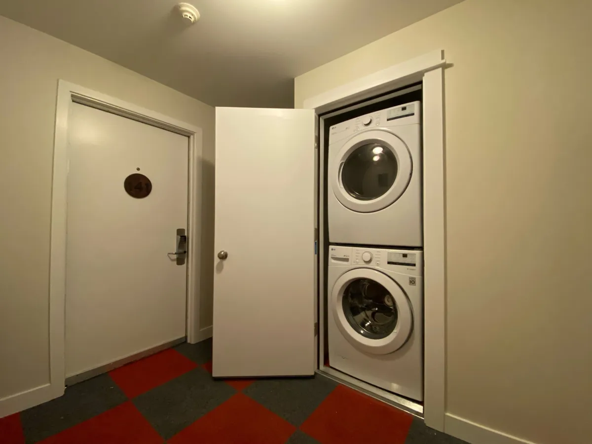 A compact, functional laundry room with a washer and dryer beside a door, emphasizing convenience and practicality for longer stays.